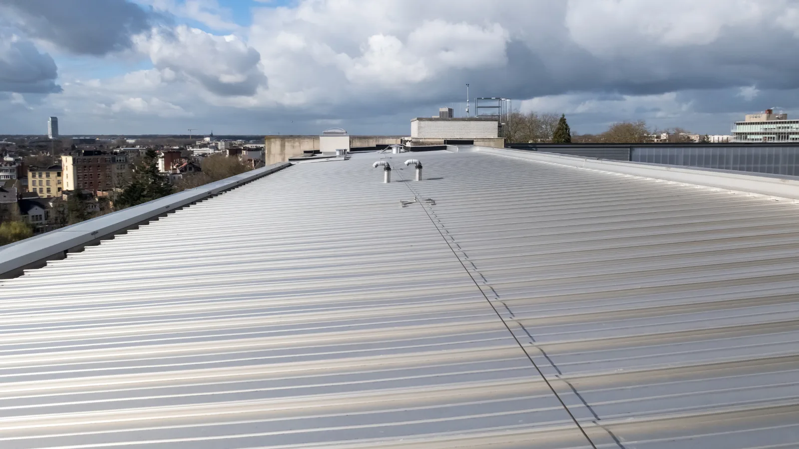 Ribbed metal commercial roof with vent pipes and raised perimeter edges